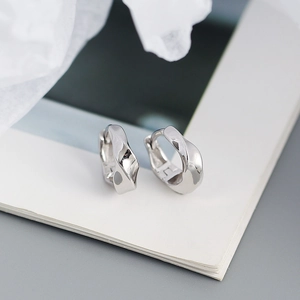 Vue détaillée de boucles d'oreilles torsadées en argent sur des pages de livre blanches