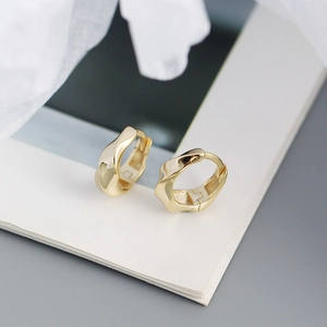 Gros plan de boucles d'oreilles créoles torsadées dorées avec finition miroir polie