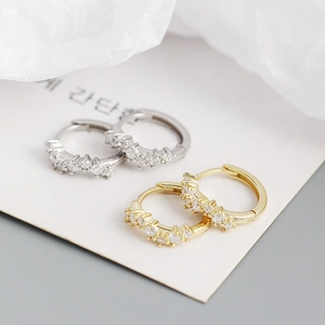 Macro view of geometric wavy hoop earrings with zircon stones in gold and silver finish