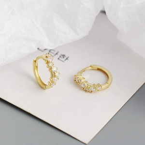 Detailed close-up of golden wavy hoop earrings featuring pave-set cubic zirconia crystals