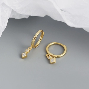 Detailed macro view of gold geometric huggie earrings with sparkling square zircon pendants