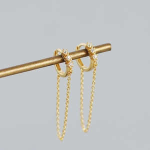 Detail of s925 silver hoop earrings with zircon accents and long hanging gold chain