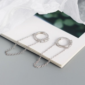 Macro shot of silver geometric hoop earrings with tassel chain and white zircons