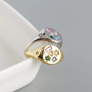 Macro shot of gold and silver signet rings with colorful star-shaped zircon inlays