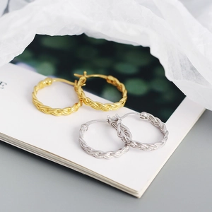 Macro di orecchini a cerchio intrecciati color oro e argento su carta bianca elegante