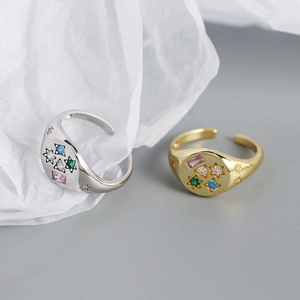 Macro shot of silver and gold rings with colorful zircons and star engraving details