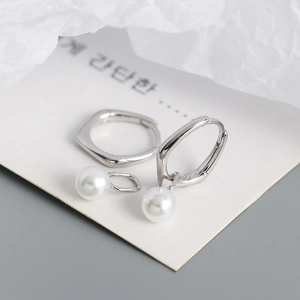 Macro detail of S925 sterling silver hoop earrings with round white pearl pendants