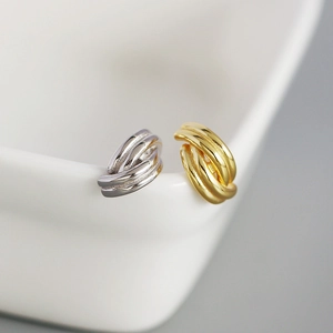 Detailed view of layered geometric metal earrings in gold and silver finish on ceramics