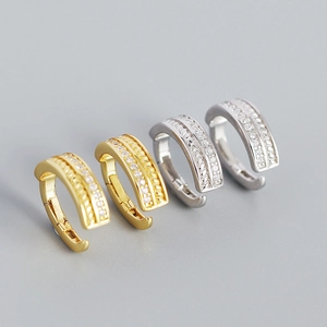 Elegant gold and silver twisted spring hoop earrings with micro-set zircons on grey background