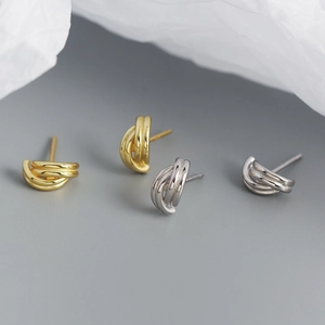 Close-up of knotted geometric stud earrings in polished gold and silver finishes