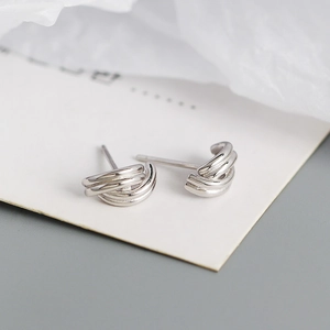 Macro detail of silver geometric layered stud earrings with a polished metallic finish