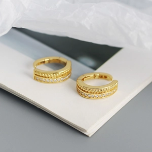 Macro shot of gold twist rope earrings with sparkling cubic zirconia on display stand