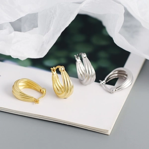 Detail of multi-layered geometric spiral hoop earrings in polished gold and silver finishes