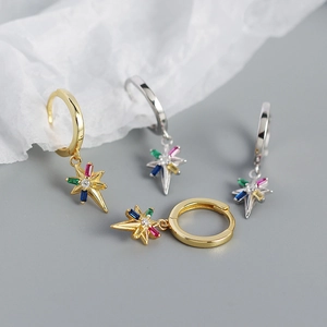 Detalle de pendientes de estrella de ocho puntas con gemas de colores variados
