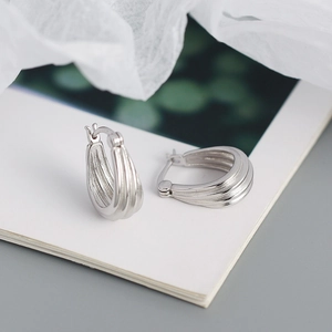 Macro shot of silver S925 geometric hoop earrings with vertical groove texture