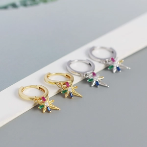Detalle macro de pendientes de estrella dorados y plateados con gemas de colores