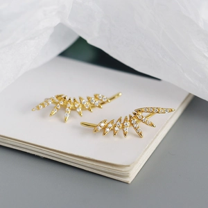 Macro shot of gold wing earrings with micro-set white zircon stones on white card