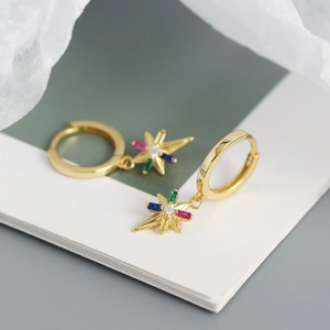 Detalle macro de pendientes de estrella dorada con incrustaciones de circonitas de colores