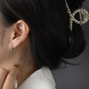 Gros plan d'une boucle d'oreille créole S925 en argent torsadé irrégulier sur un mannequin