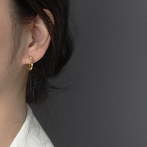 Gros plan de boucles d'oreilles créoles torsadées dorées portées par un mannequin de mode