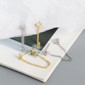 Close-up of gold and silver rectangle zircon stud earrings with long chain tassels