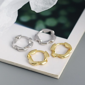 Gros plan de boucles d'oreilles torsadées en argent s925, finitions dorée et argent