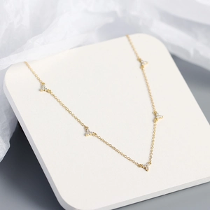 Detail view of gold necklace with five clover charms featuring micro-set zircon stones