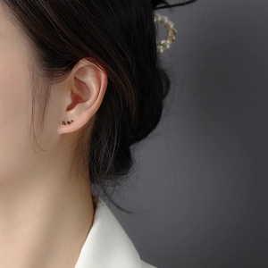 Detailed view of minimalist gold stud earrings with three graduated black cubic zirconias