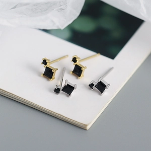 Macro detail of geometric square black zircon earrings in gold and silver finishes