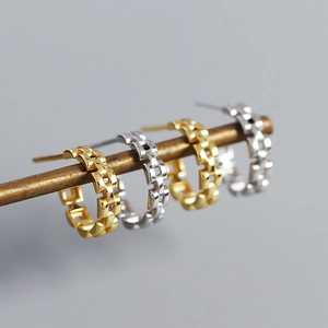 Macro shot of S925 silver C-shape earrings with vintage watchband chain texture