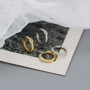 Detail view of gold and silver huggie hoop earrings with oval crystals on photo cards