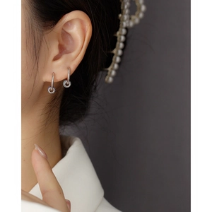 Detail of S925 silver hoop earrings with blue pavé charms worn by a model