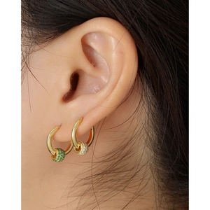 Macro detail of 18K gold hoop earrings with emerald and clear zircon pavé beads