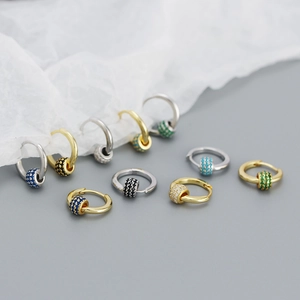 Macro view of gold and silver huggie hoop earrings with multi-colored gemstone beads