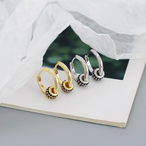 Detail of gold and silver hoop earrings with black micro-pave moving beads on white paper
