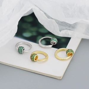 Detailed close-up of S925 silver hoop earrings with rotating green crystal beads