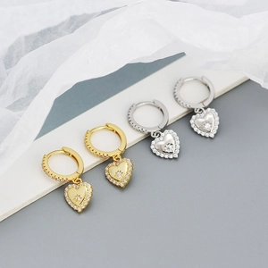 Detail of silver heart hoop earrings with sparkling zircons and starburst center