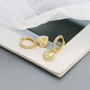 Close-up of gold heart drop earrings with starburst engraving and cubic zirconia stones