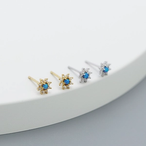Detailed view of silver and gold flower stud earrings with blue opal and small zircons