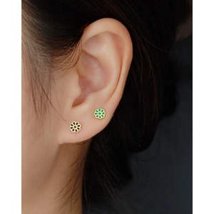 Close-up of small daisy enamel stud earrings on ear featuring gold edges and dark petals