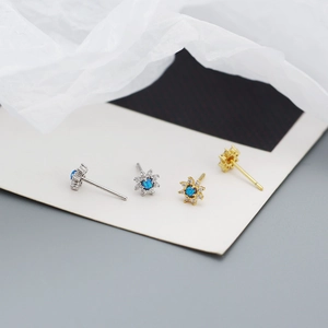 Close-up of sunflower studs in gold and silver with blue opal and small white zircons