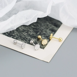 Detailed macro view of daisy stud earrings in gold and silver with screw-back closures