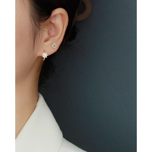 Vue détaillée de boucles d'oreilles fleur en or avec pierres bleues et diamants