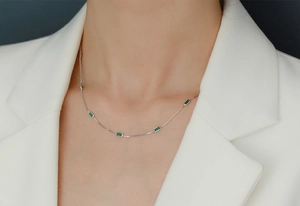 Macro view of dainty S925 silver necklace featuring five emerald-cut green zircon stones