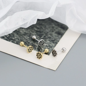 Close-up of four floral S925 silver stud earrings with black oil drip on vintage paper