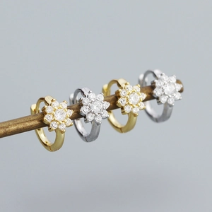 Gros plan de boucles d'oreilles fleurs en argent et or avec des zircons brillants