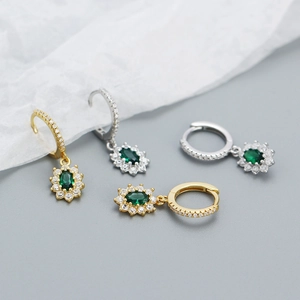 Détail de boucles d'oreilles luxe en émeraude et zircon avec finition or et argent