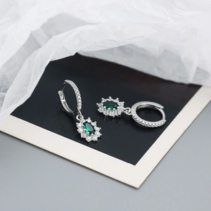 Détail des boucles d'oreilles en zircon vert émeraude avec monture fleur en argent S925