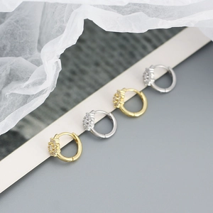Détail de boucles d'oreilles créoles avec fleurs en zircon sur support d'affichage