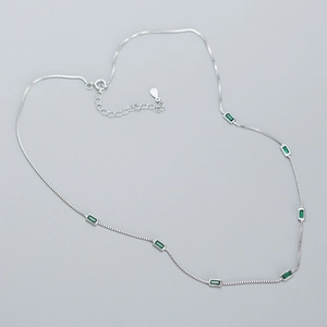 Detailed view of silver box chain with seven rectangular emerald cubic zirconia stones